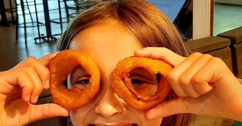 child holding onion rings over eyes